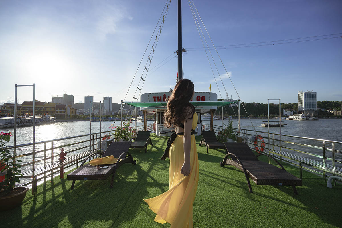Bảng giá tàu ghép thăm vịnh Hạ Long 2025 mới nhất 17 du khách thích thú chụp ảnh trên sundeck boong tàu được trải thảm cỏ xanh bắt mắt
